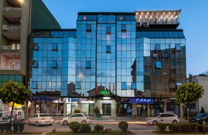 A modern hotel with a glass facade, a dental clinic, and a visible sign for 'GILI' hotel.