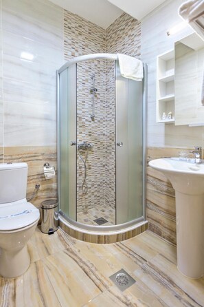A bathroom with a glass-enclosed shower, a toilet, and a sink.