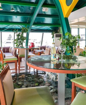 A restaurant with a glass table, seating, and a view of the outside. - Green Center Gili (Gostivar)