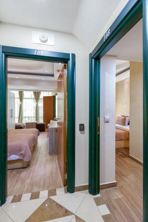 A hotel corridor with a bed, a desk, and a bathroom visible. - Green Center Gili (Gostivar)