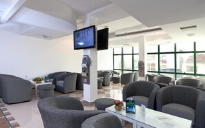 A hotel lobby with seating, a TV, and a bulletin board.