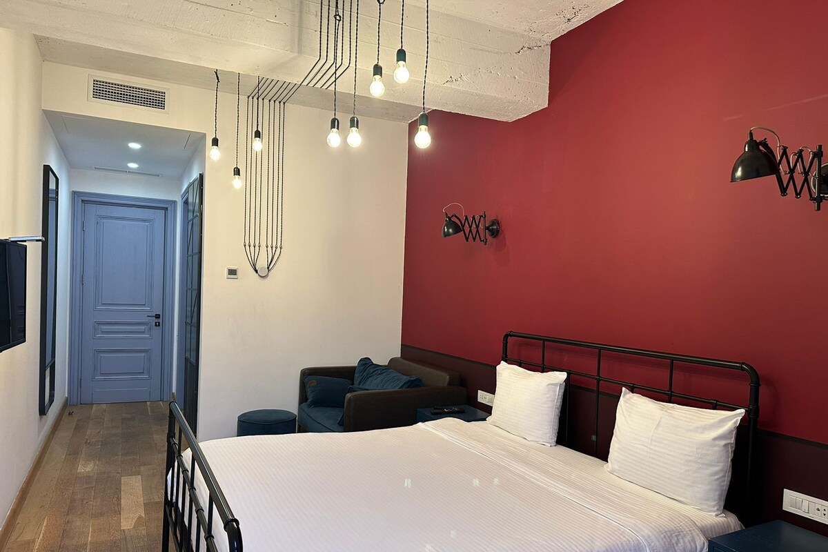 A bedroom with a bed, bedside table, and a red accent wall.