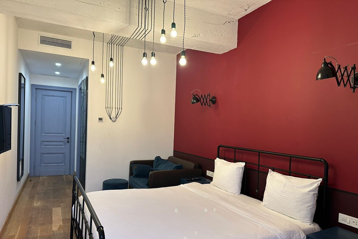 A bedroom with a bed, bedside table, and a red accent wall.