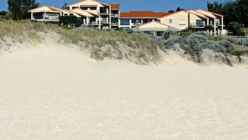 A beachfront property with multiple buildings, including a two-story structure with a red roof and a single-story building with a similar roof design.