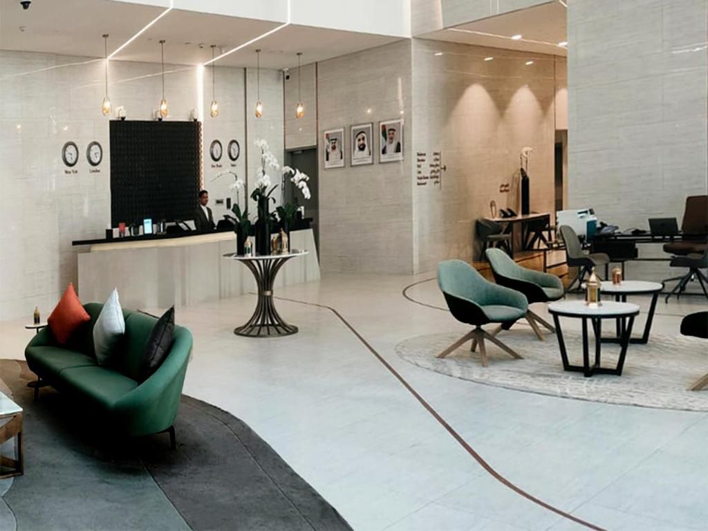 A modern lobby with a reception desk, seating area, and a large mirror.