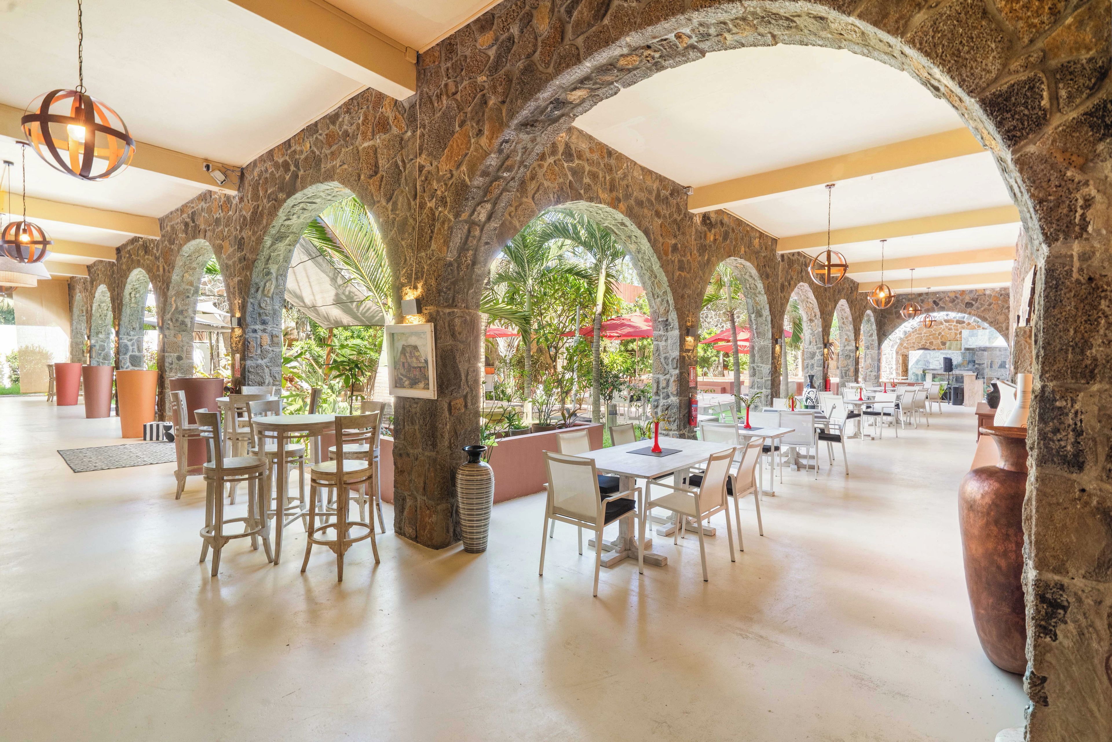 Un comedor interior con arcos de piedra, mesas y sillas.