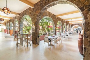 Un comedor interior con arcos de piedra, mesas y sillas.