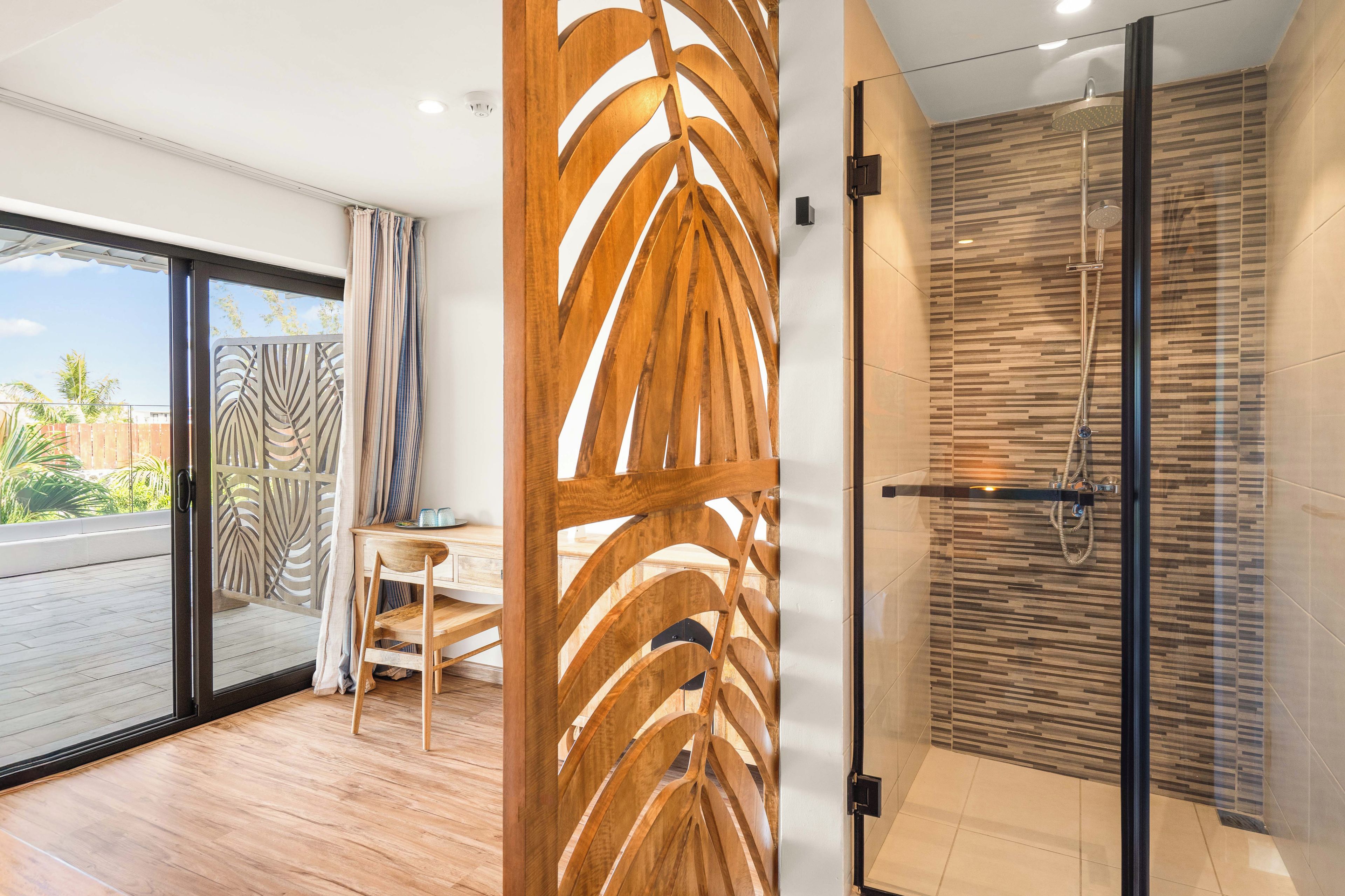 Un baño moderno con cabina de ducha de vidrio, un panel decorativo de madera y vistas al exterior.
