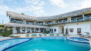 Ein Resort mit Schwimmbad, strohgedeckten Gebäuden und Liegestühlen.