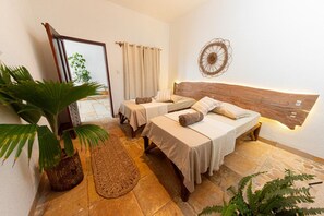 A hotel room with a bed, two bedside tables, a mirror, a potted plant, and a decorative wall piece.