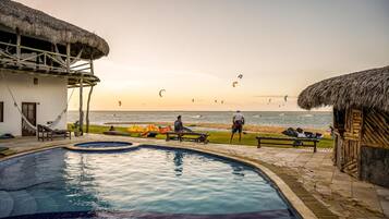 A swimming pool with a view of the beach and kitesurfing activity.