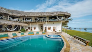 Ein Resort mit Pool, strohgedeckten Gebäuden und Meerblick.