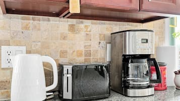 A kitchen with a coffee maker, toaster, and kettle.