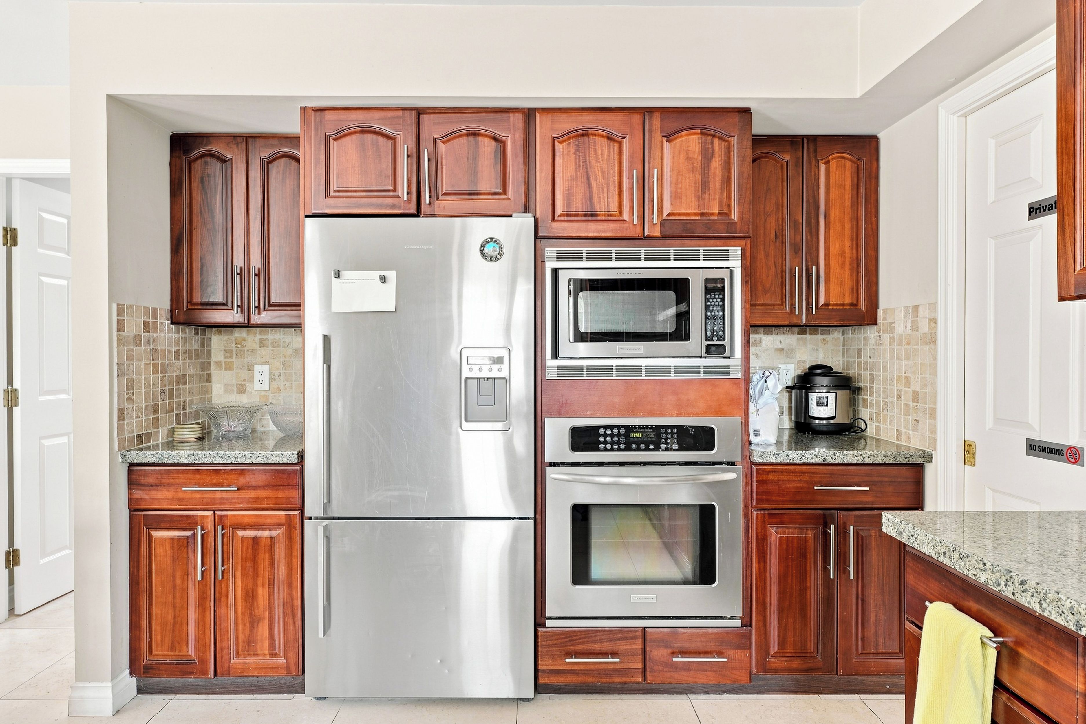 A kitchen with wooden cabinets, a stainless steel refrigerator, a microwave, an oven, and a coffee maker.