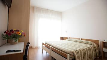 Quarto com cama, escrivaninha, cadeira, mesa de cabeceira e janela com cortinas.