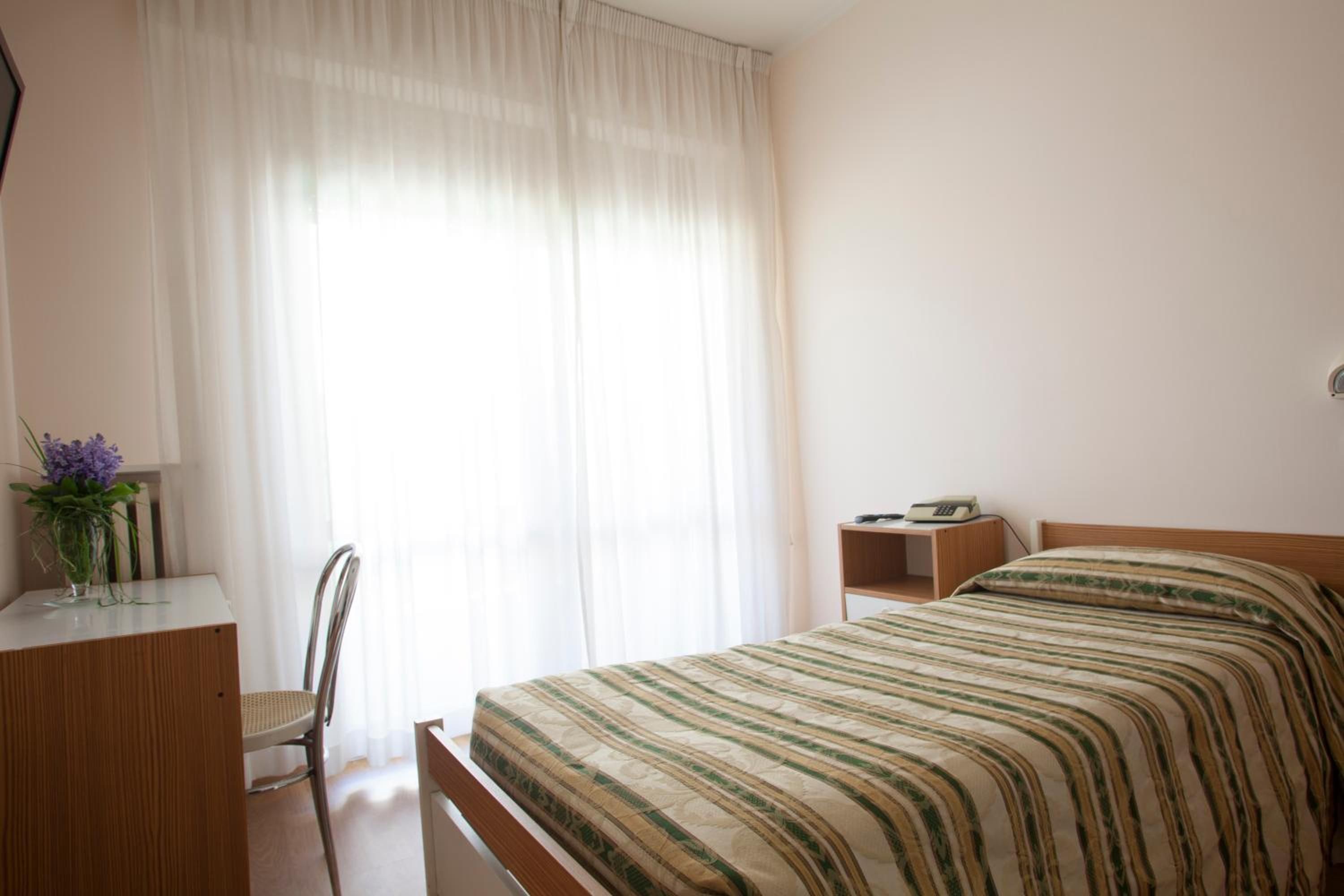 Una camera da letto con un letto, una scrivania, una sedia e un comodino.