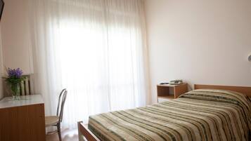 Una camera da letto con un letto, una scrivania, una sedia e un comodino.