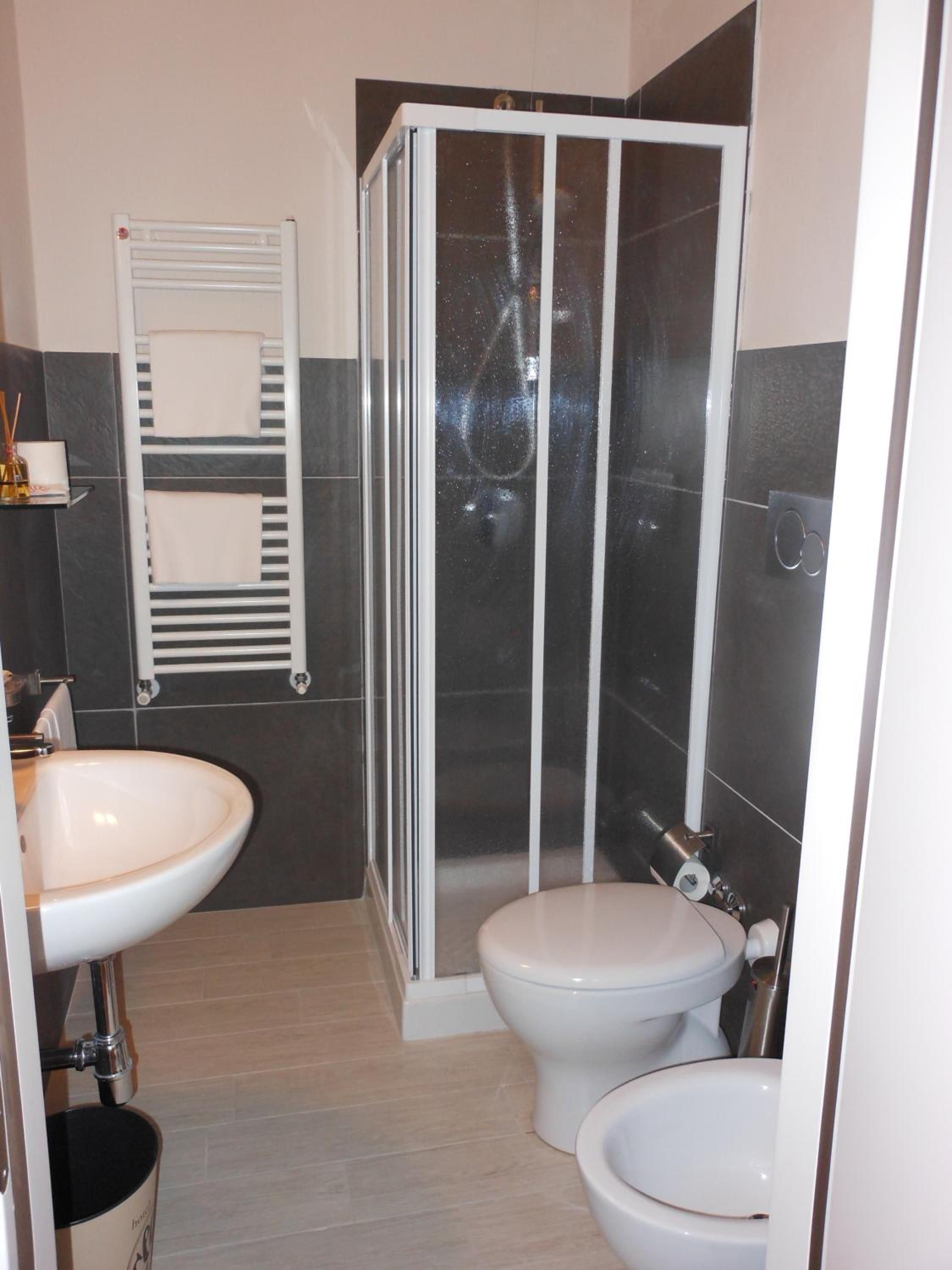 Un bagno con un lavandino bianco, un WC e una cabina doccia in vetro.