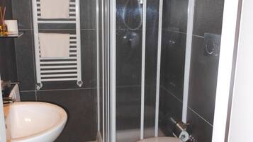 Un bagno con un lavandino bianco, un WC e una cabina doccia in vetro.