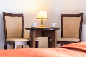 Una habitación de hotel con una cama, una mesa y dos sillas, y una lámpara.