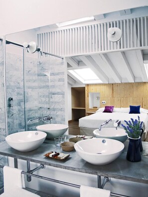 Un baño moderno con dos lavamanos grandes, un espejo y una zona de ducha.