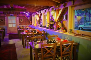 Un ristorante con tavoli e sedie di legno, un'area bar con bottiglie e vista sulla strada.
