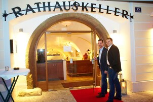 Entrada de un hotel con un amplio arco, una recepción en el interior y una alfombra roja que conduce a la entrada.