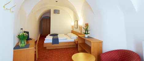 Una habitación compacta con cama, escritorio, silla y una pequeña mesa.