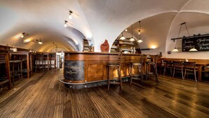 Interior de restaurante con piso de madera, barra central y techo abovedado.