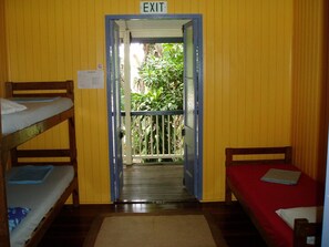 A room with bunk beds, an exit sign, and a view of greenery outside. - Mango Tourist Hostel (Hervey Bay)