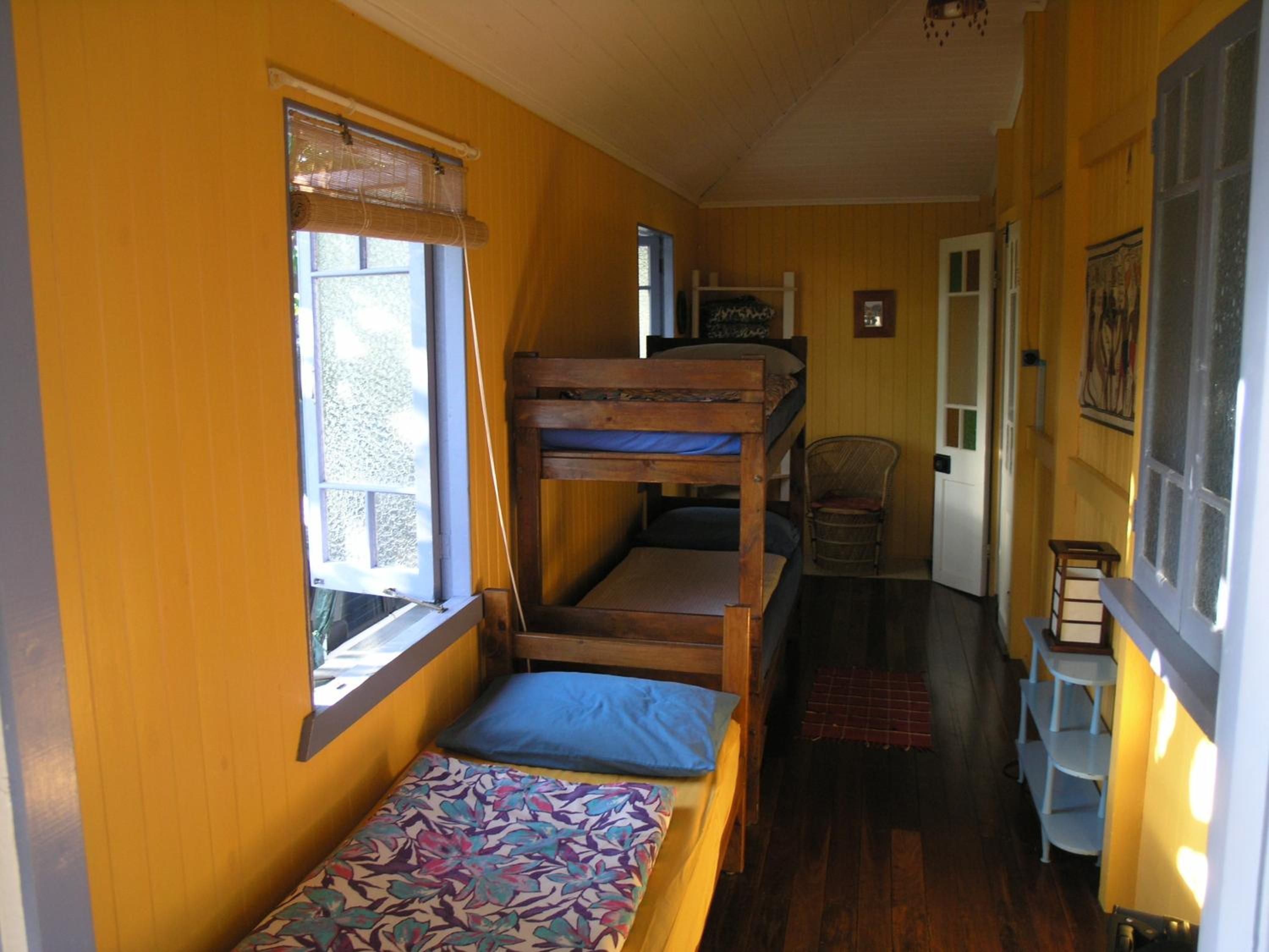 Une chambre avec un lit superposé, une fenêtre, une chaise et une petite table.