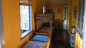 Habitación con literas, ventana, una silla y una mesita.
