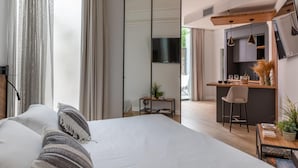 A modern hotel room with a large bed, a desk, a kitchenette, and a TV. - Livia Valeria Palace (Rome)