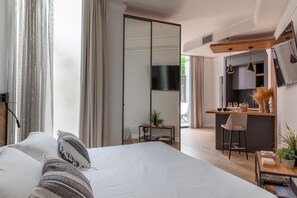 A modern hotel room with a large bed, a desk, a kitchenette, and a TV. - Livia Valeria Palace (Rome)