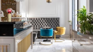 A modern interior with a marble floor, a tufted grey sofa, a blue armchair, and a yellow chair. - Livia Valeria Palace (Rome)