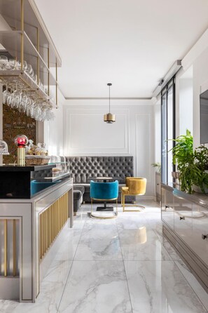 A modern interior with a marble floor, a tufted grey sofa, a blue armchair, and a yellow chair. - Livia Valeria Palace (Rome)