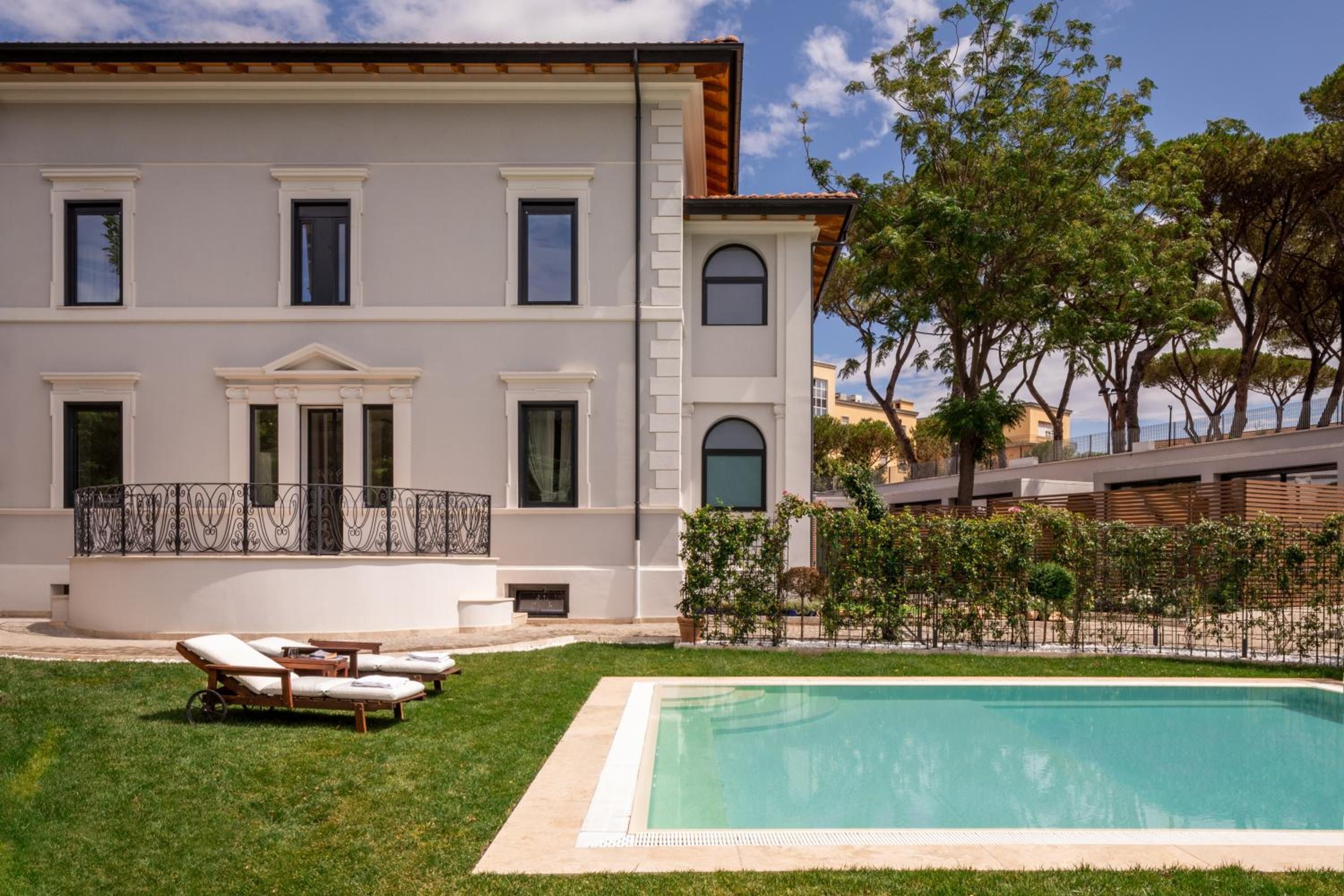 Um edifício de dois andares com piscina, área de estar externa e um jardim bem cuidado.