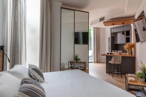 A modern hotel room with a large bed, a desk, a kitchenette, and a TV. - Livia Valeria Palace (Rome)