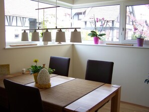 Un coin repas comprenant une table, des chaises, une lampe et une fenêtre agrémentée de plantes.