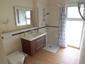 Une salle de bain moderne équipée d’une douche, de toilettes et d’un meuble-lavabo.