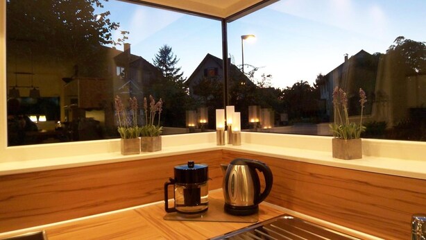 A modern kitchen with large windows, wooden countertops, a coffee maker, and a kettle. - Badische Landoase (Kehl)