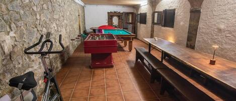 A room with a foosball table, a stationary bike, and a billiards table.