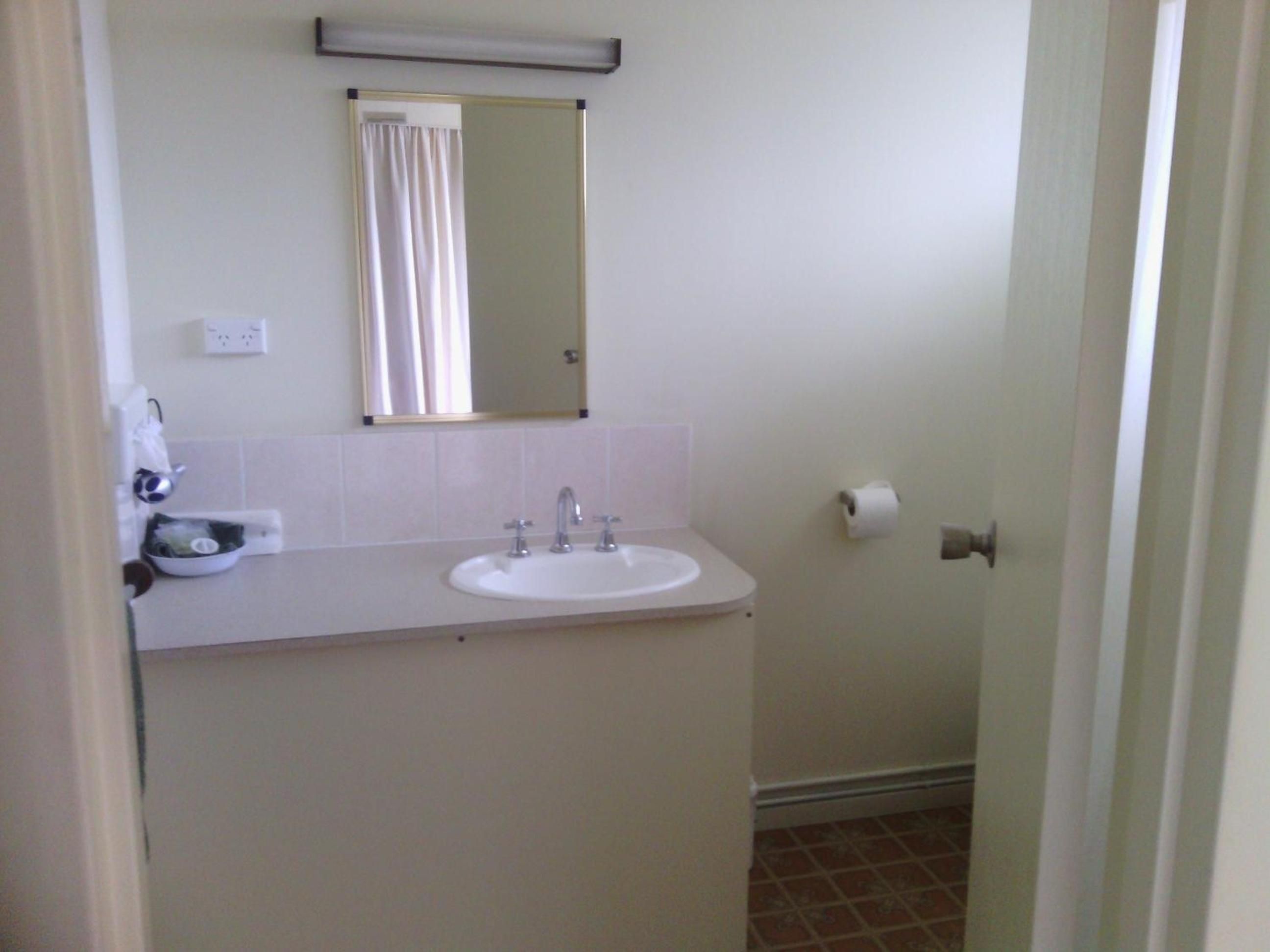 A bathroom with a sink, mirror, and toilet paper.