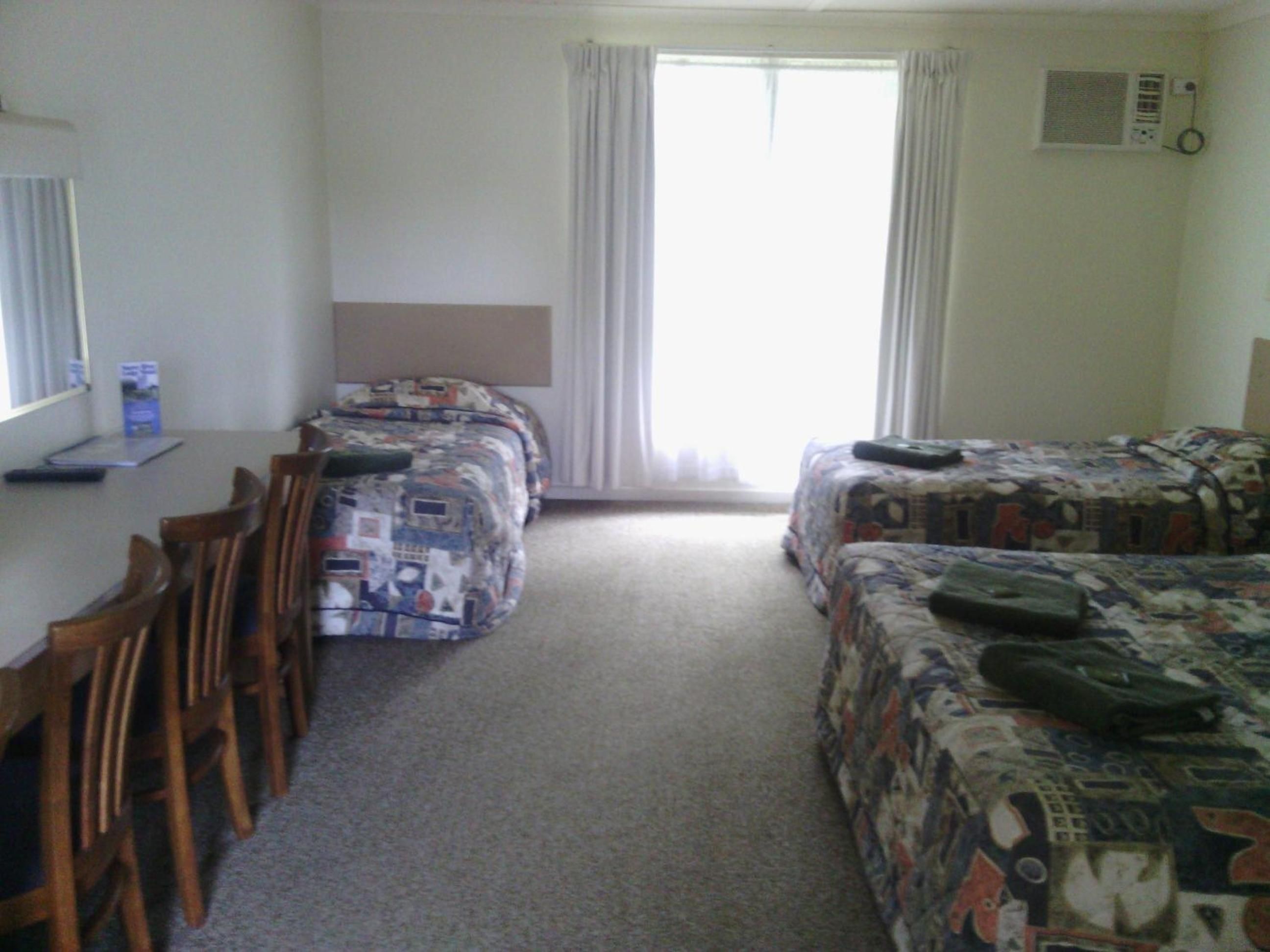 A room with two beds, a desk, and a chair.