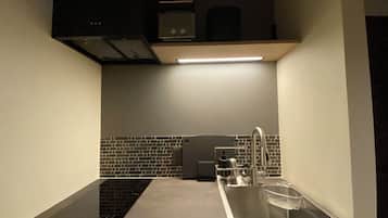A kitchen with a modern design, featuring a stainless steel sink, a black backsplash, and a built-in oven.