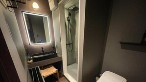 Een moderne badkamer met een douchecabine van glas, een wit toilet en een wastafel met spiegel.