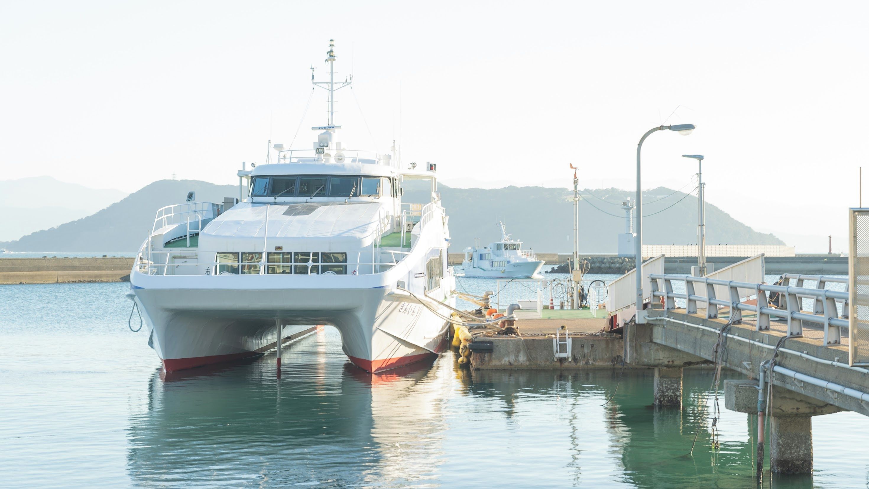 A ferry docked at a pier with a mountainous backdrop.
