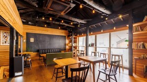 Een gezellig café met houten wanden, een schoolbord en diverse zitmogelijkheden, zoals tafels en stoelen.