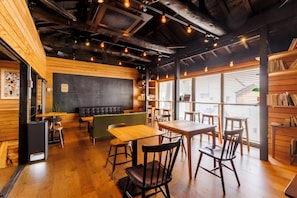 A cozy cafe with wooden walls, a blackboard, and a variety of seating options including tables and chairs. - HITOYOI SENRI Rooftop BBQ Ocean View (Fukuoka)