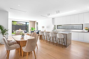A modern kitchen with a central island, bar stools, and a dining area with a round table and chairs.